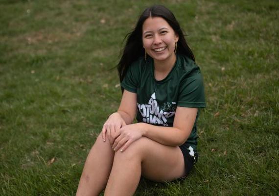 Amy Tse sitting on a field. 